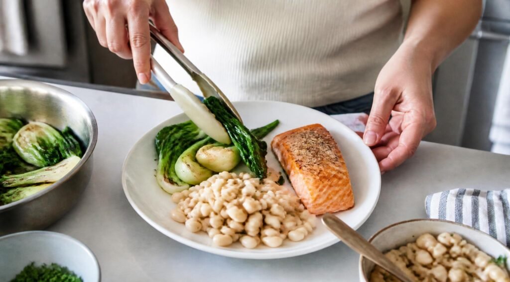 gpt image 2 A person s hands arranging sauteed bok choy baked salmon and white beans onto a 0